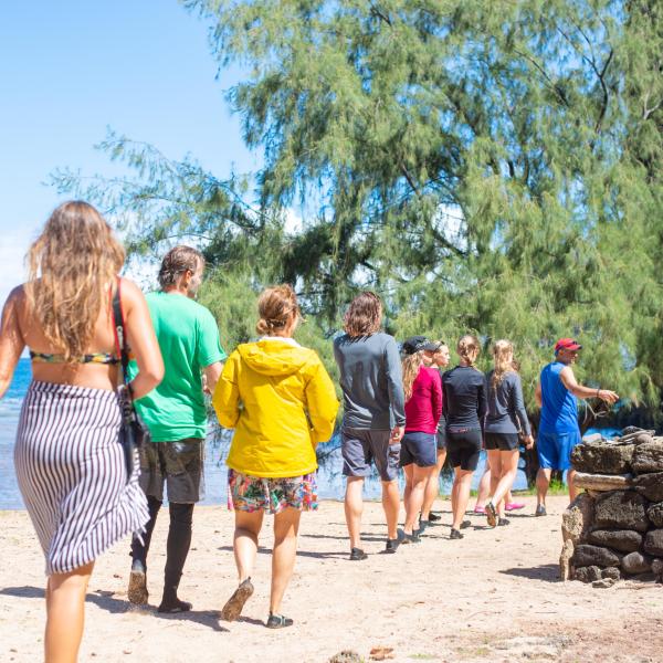 a group of people standing on top of a sandy beach in Kauai