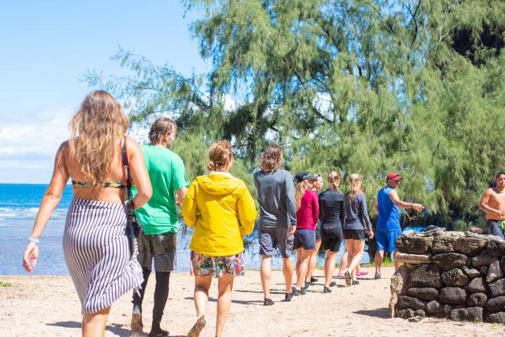a group of people standing on top of a sandy beach in Kauai