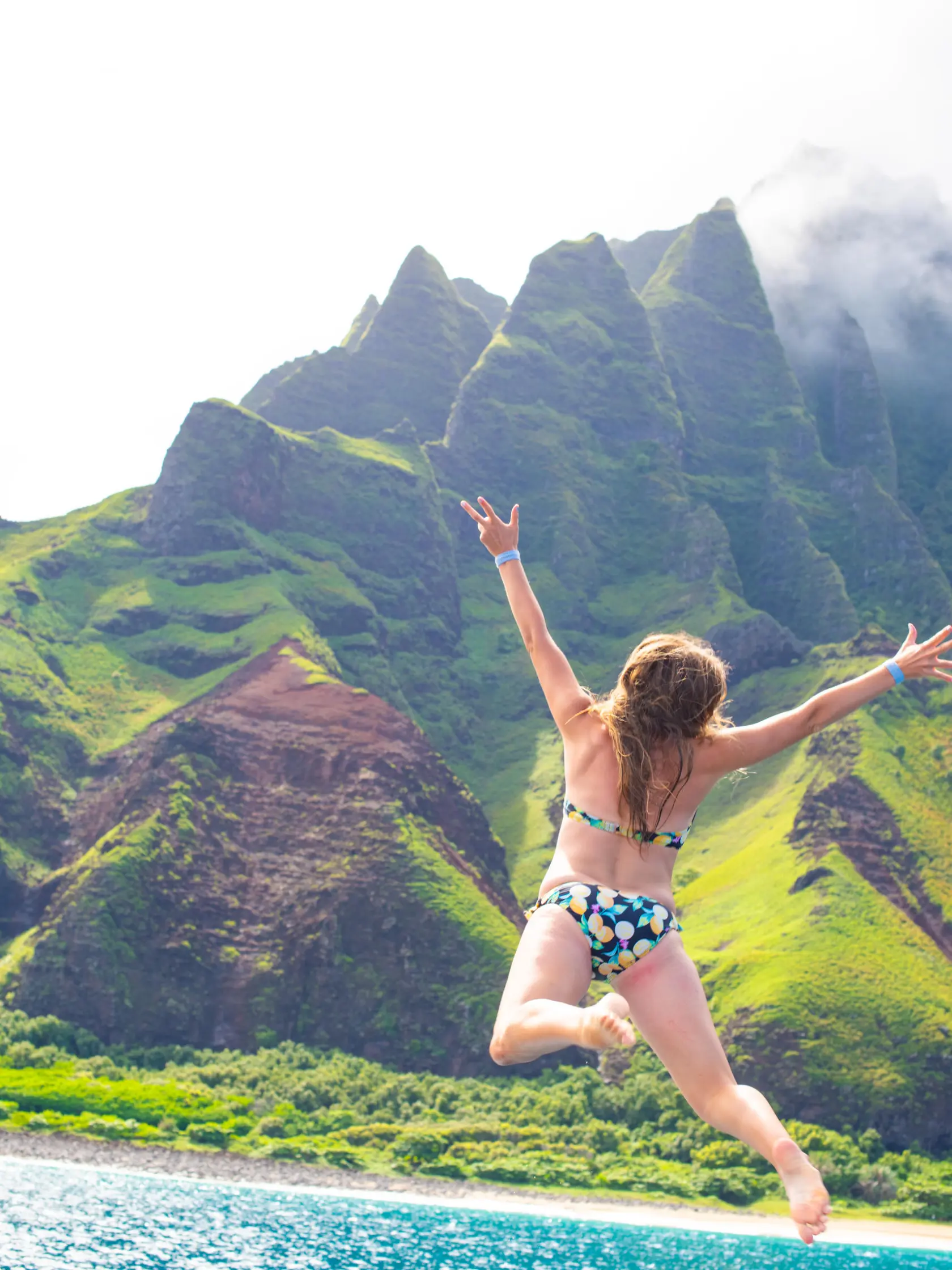a man standing in a body of water with a mountain in the background