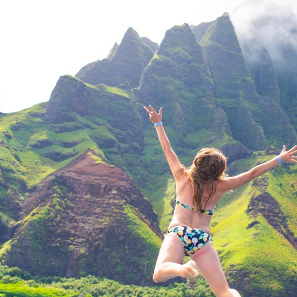 a man standing in a body of water with a mountain in the background