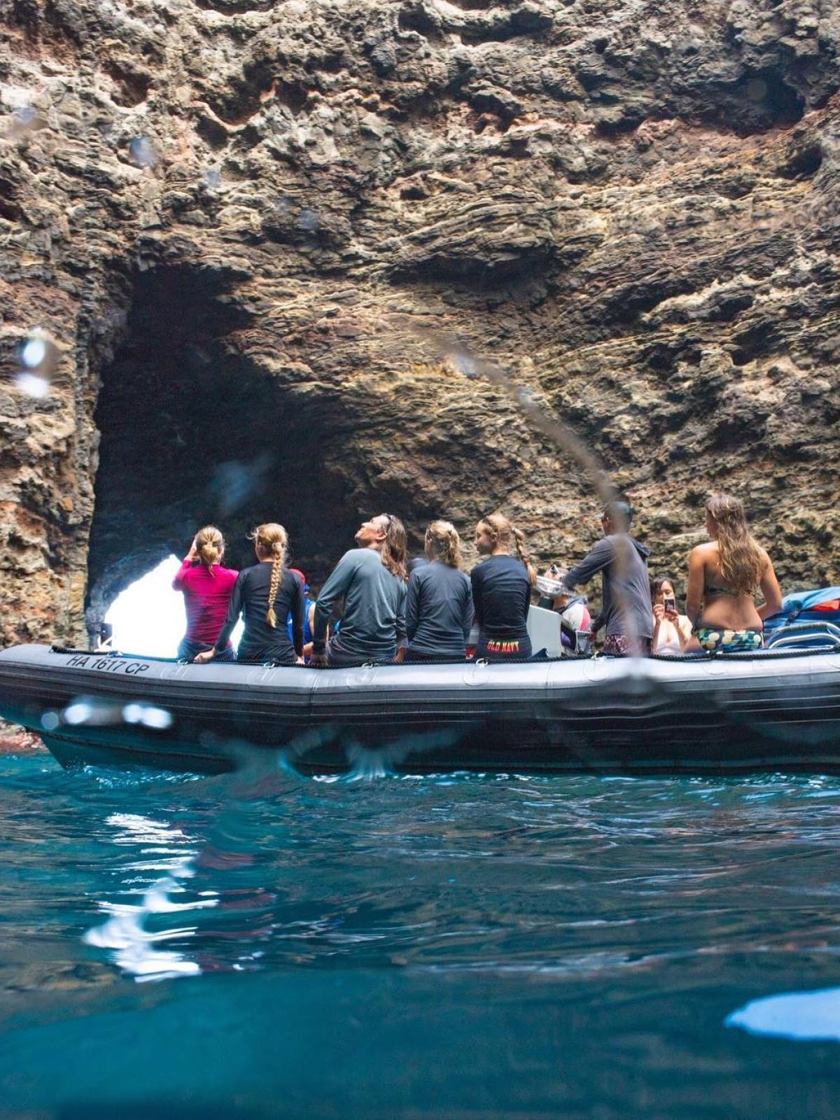 a group of people riding on the back of a boat in the water