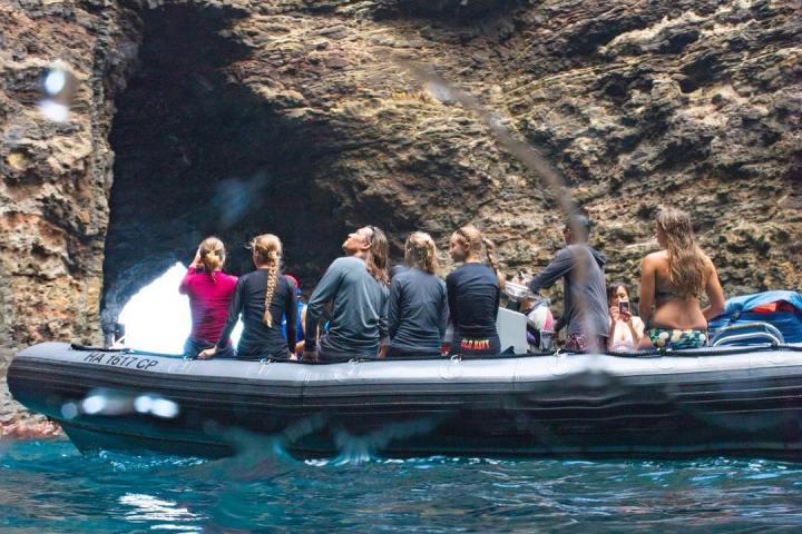 a group of people riding on the back of a boat in the water