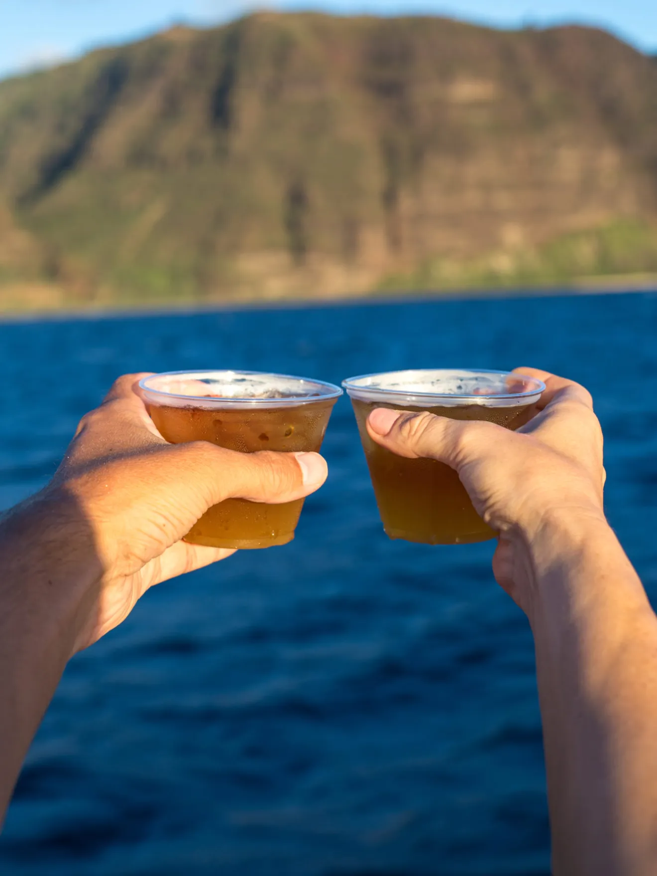 a hand holding a water bottle in front of a body of water