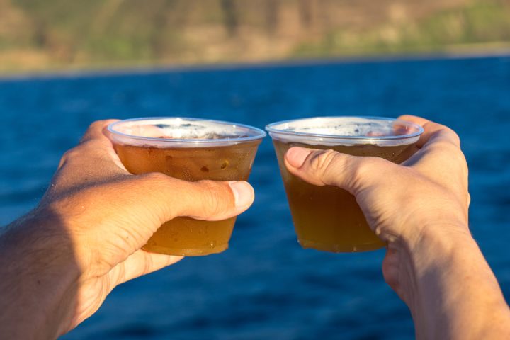 a hand holding a water bottle in front of a body of water
