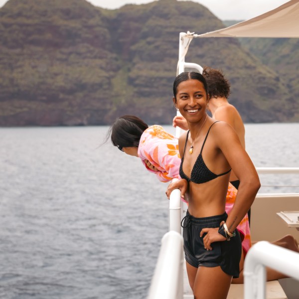 Smiling person in a bikini on a boat, with mountains in the background.