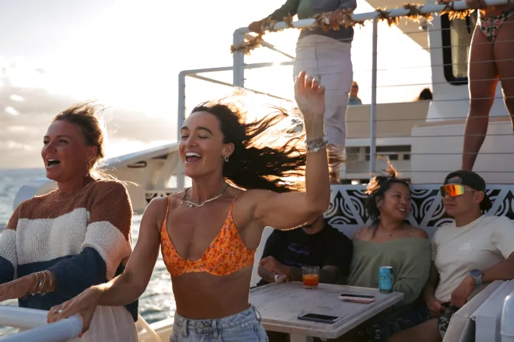 People enjoying a sunny day on a boat with one dancing and others relaxing.