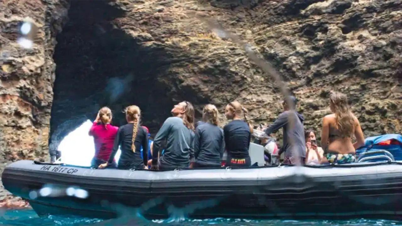 Group on a raft near a rocky cave over turquoise water.